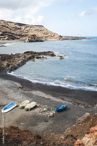 Boats on the black sand beach on the rocky point of El Golfo - Lanzarote, Spain