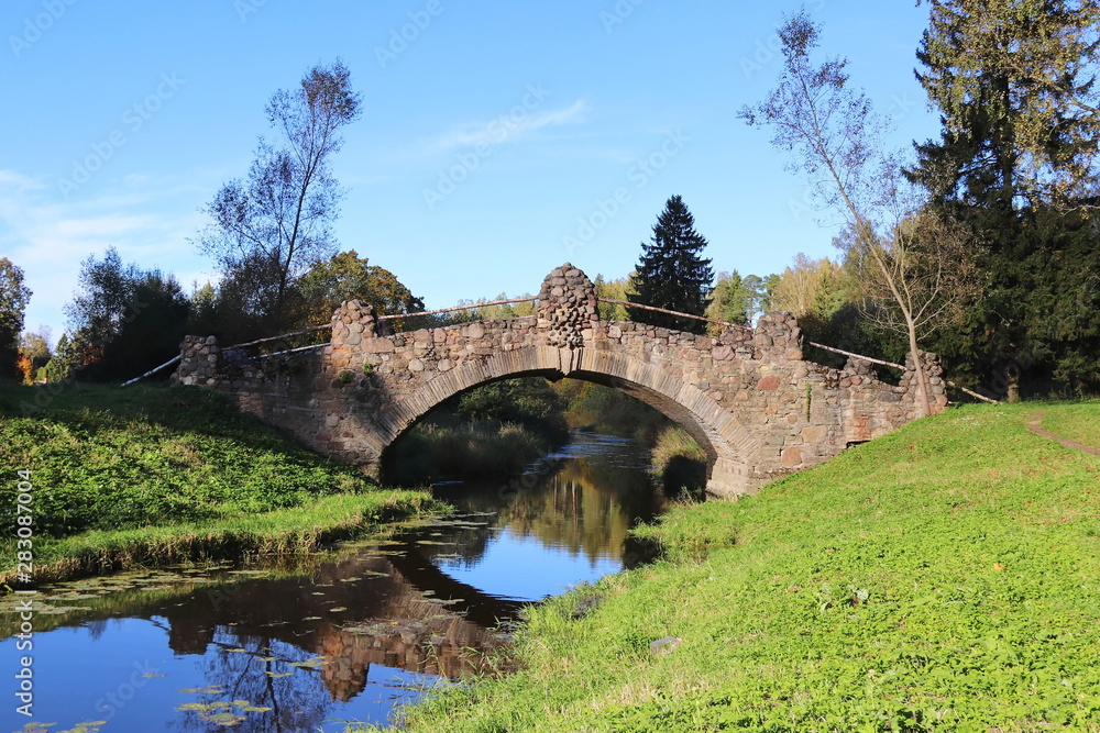 Old historical stone bridge on small river in the forest