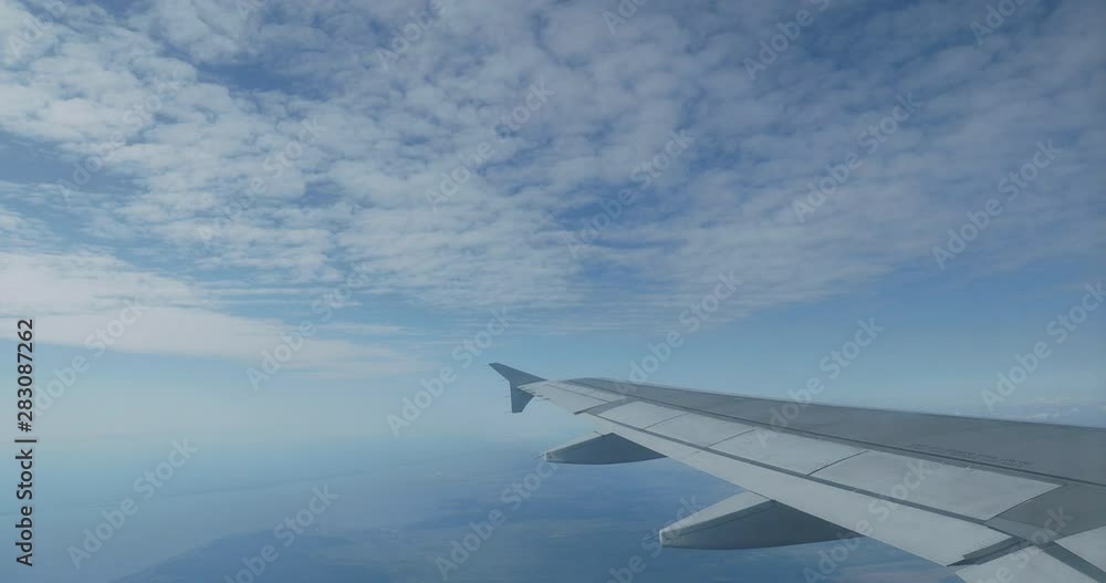 View on blue sky and fluffy white clouds through the window of the aircraft. Scenic view from flying airplane. View on blue sky and fluffy white clouds through the window of the aircraft. Scenic view from flying airplane.