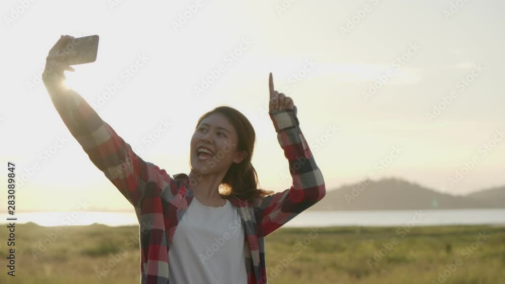 Attractive young Asian woman selfie video chat with her friends on the smartphone while sunset having fun together a summer traveling. Asian friends' lifestyle travels holiday vacation time. Attractive young Asian woman selfie video chat with her friends on the smartphone while sunset having fun together a summer traveling. Asian friends' lifestyle travels holiday vacation time.