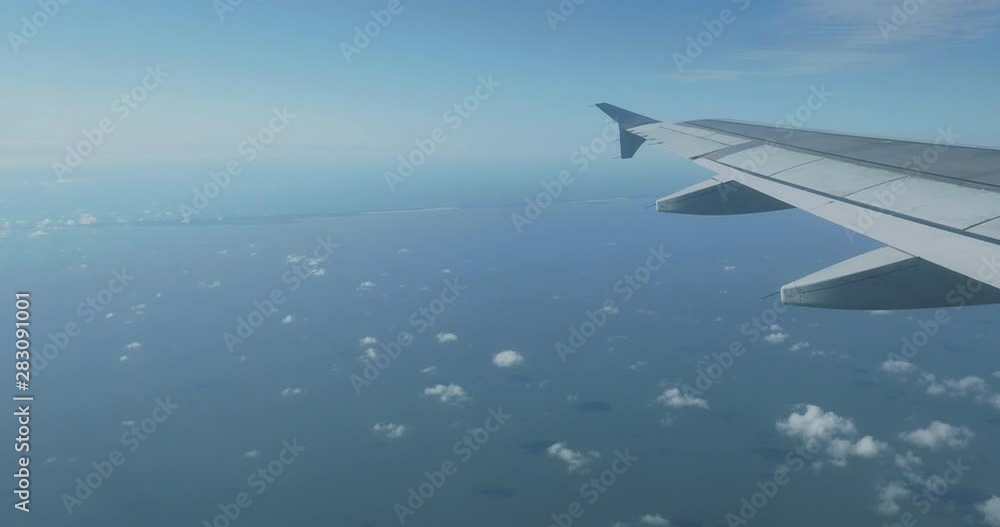 View on blue sky and fluffy white clouds through the window of the aircraft. Scenic view from flying airplane. View on blue sky and fluffy white clouds through the window of the aircraft. Scenic view from flying airplane.