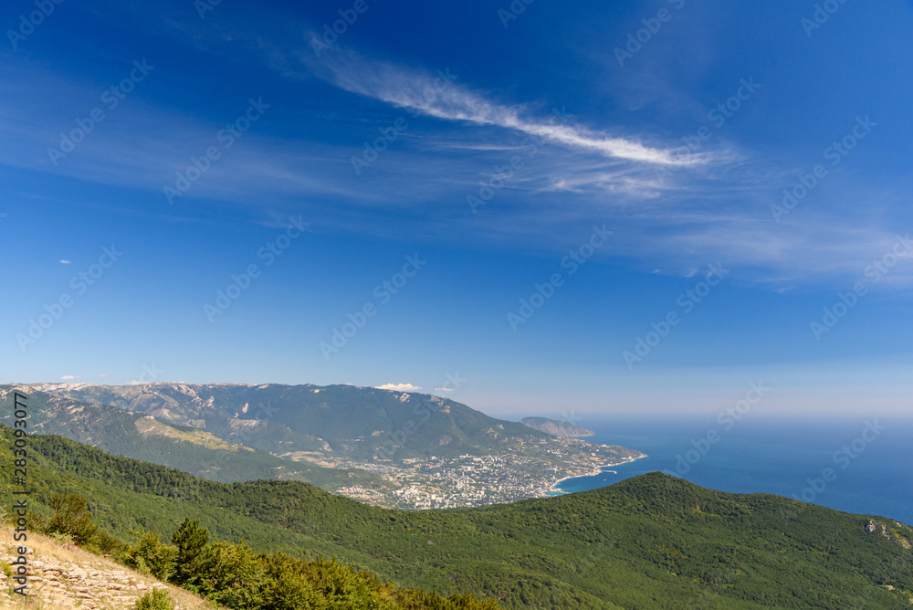 view of the resort city of Yalta, on a bright sunny day with clouds in the sky.