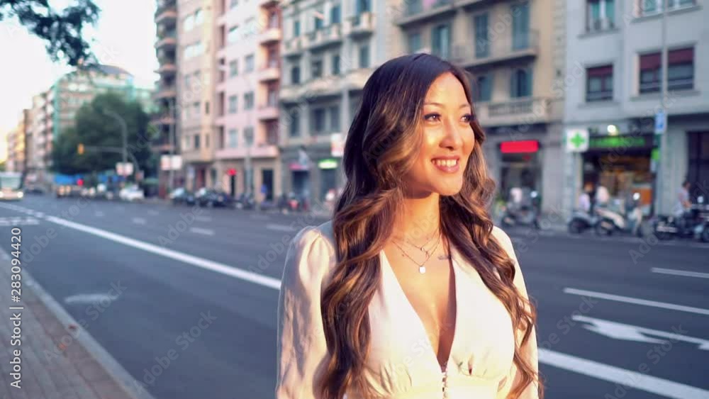 Summer sunny lifestyle portrait of young stylish asian girl on the street of big modern city. She wears white dress. women business Summer sunny lifestyle portrait of young stylish asian girl on the street of big modern city. She wears white dress. women business