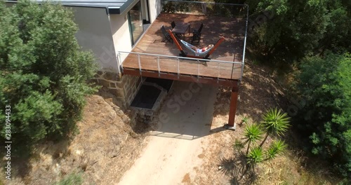 Woman in a hammock, Aerial, reverse, drone shot, of a girl relaxing at a cabin, over a resort, with a vineyard, a pool and fruit garden, at the Douro river, on a sunny day. in Portinha, Portugal photo