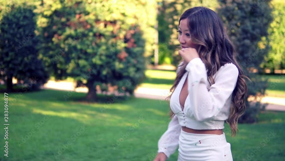 Beautiful Asian girl smiling in the park. She is wearing white dress. Happy video Beautiful Asian girl smiling in the park. She is wearing white dress. Happy video
