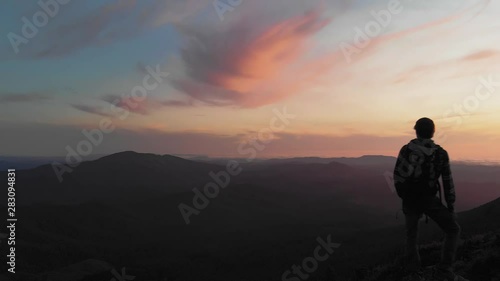 Person standing on rock with epic mountain viewpoint with a colorful sunset drone aerial landscape shot photo