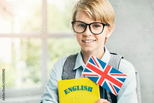 Smiling blond pupil with textbooks and british banner