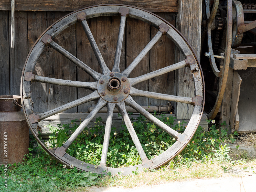 old wooden wagon wheel leaning against a wooden wall