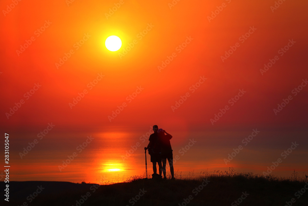 Silhouettes of a guy and a girl at sunrise by the sea photograph