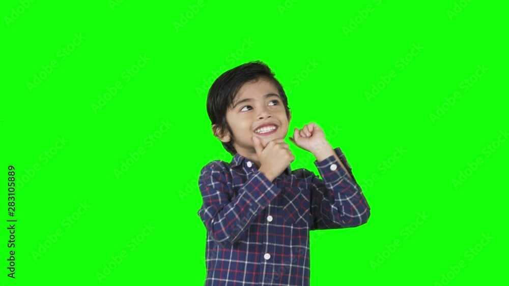 Happy little boy thinking idea while pointing up in the studio. Shot in 4k resolution with green screen background Happy little boy thinking idea while pointing up in the studio. Shot in 4k resolution with green screen background