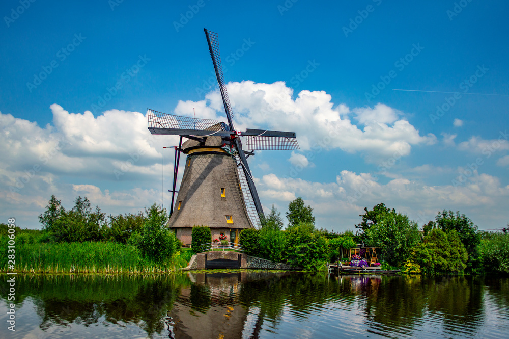 Pictureqsue rural scene with traditional Dutch windmill near the canal in Kinderdijk, Netherlands.