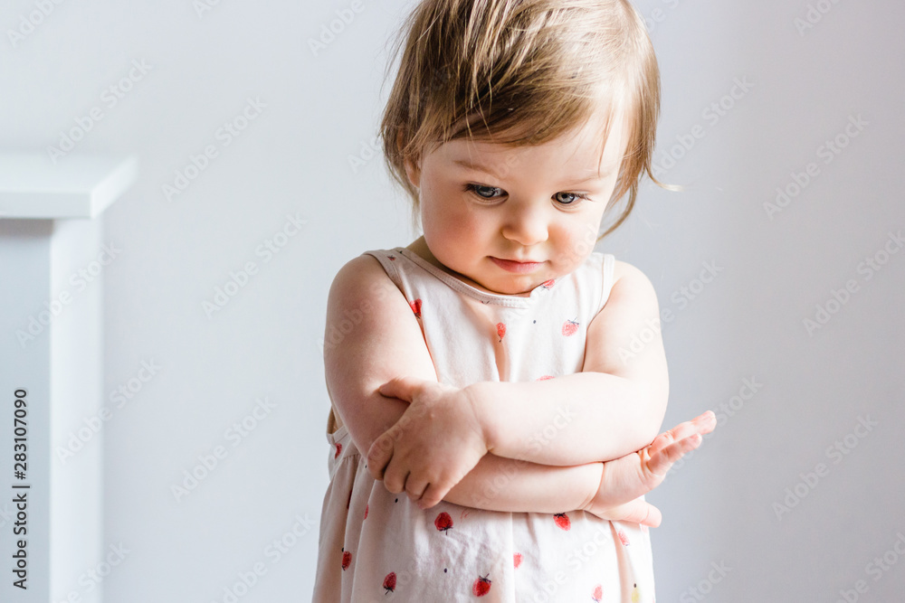 Sad toddler baby girl looking down with her arms crossed Sad toddler baby girl looking down with her arms crossed