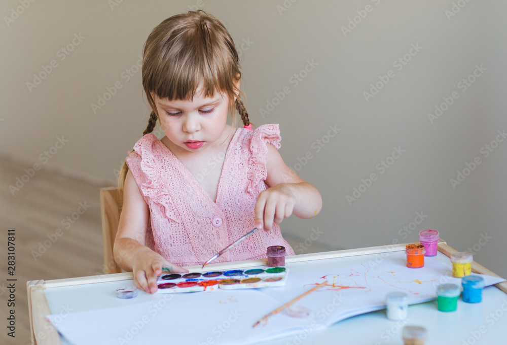Little girl painting in her room