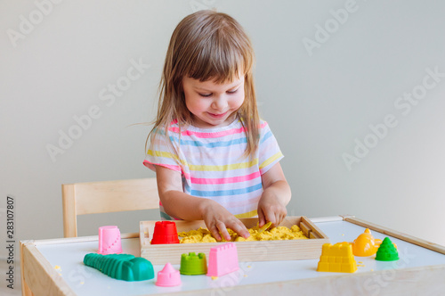 Little girl playing with colorful kinetic sand