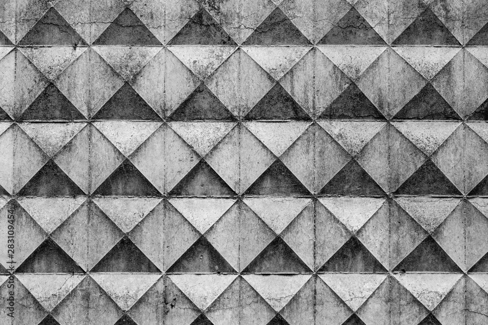 Part of a light concrete fence with rhombuses. White relief concrete wall with geometric shapes