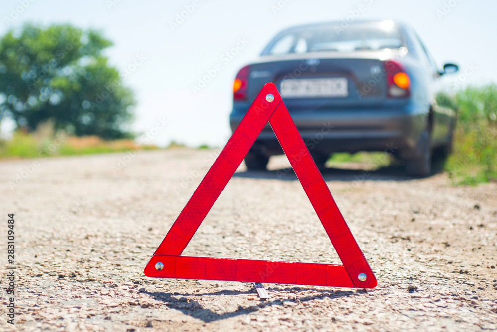 Red warning triangle with a broken down car. A car with a breakdown alongside the road