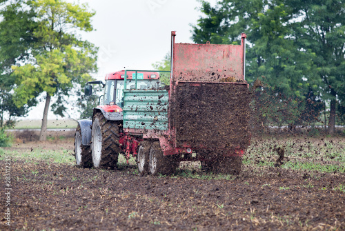 Vászonkép Tractor fertilizing field with dunk