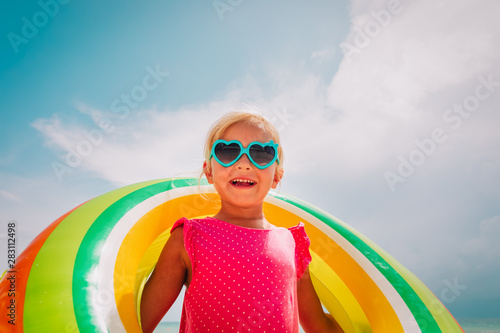 happy cute little girl with floating ring at beach