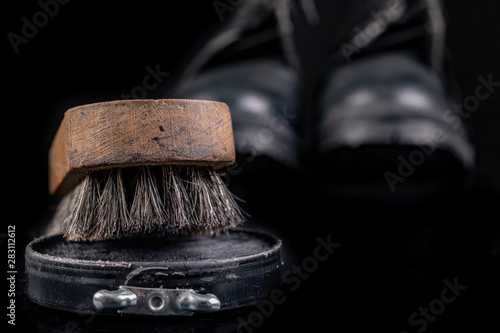 Black shoe polish, brush and shoes on the table. Accessories for cleaning leather footwear.