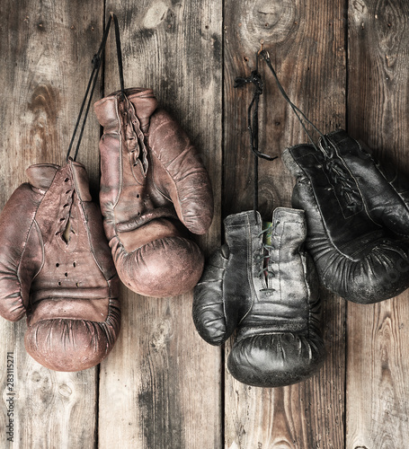 two pairs of leather vintage boxing gloves hanging on a nail © nndanko