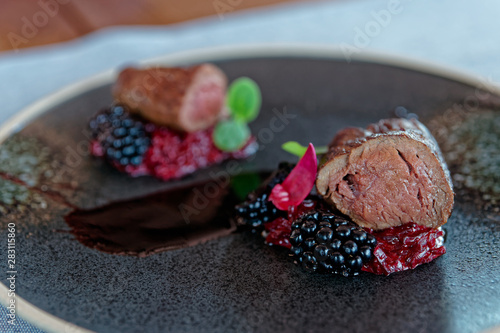 Foto Venison fillet on dark plate, close-up