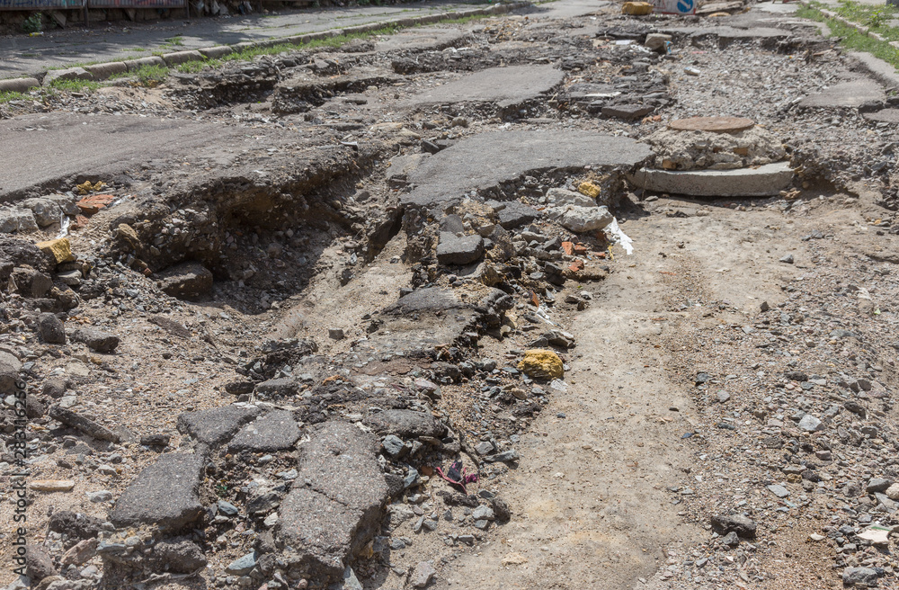 Large cracks, chips. Broken asphalt shifted landslide after flood. Destroyed road by water. Groundwater flushing. Concept of destruction of roads from nature. Consequences of flood. Broken street Large cracks, chips. Broken asphalt shifted landslide after flood. Destroyed road by water. Groundwater flushing. Concept of destruction of roads from nature. Consequences of flood. Broken street