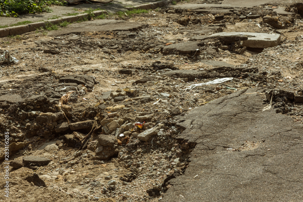Large cracks, chips. Broken asphalt shifted landslide after flood. Destroyed road by water. Groundwater flushing. Concept of destruction of roads from nature. Consequences of flood. Broken street Large cracks, chips. Broken asphalt shifted landslide after flood. Destroyed road by water. Groundwater flushing. Concept of destruction of roads from nature. Consequences of flood. Broken street