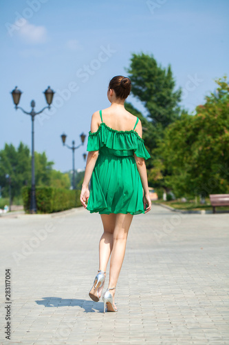 Young beautiful brunette girl in green dress walks along the embankment of the river Volga in Samara © Andrey_Arkusha