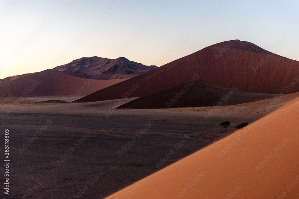 The rising sun illuminating the mighty dunes of the sossusvlei, as seen from dune 45, in Nambia.