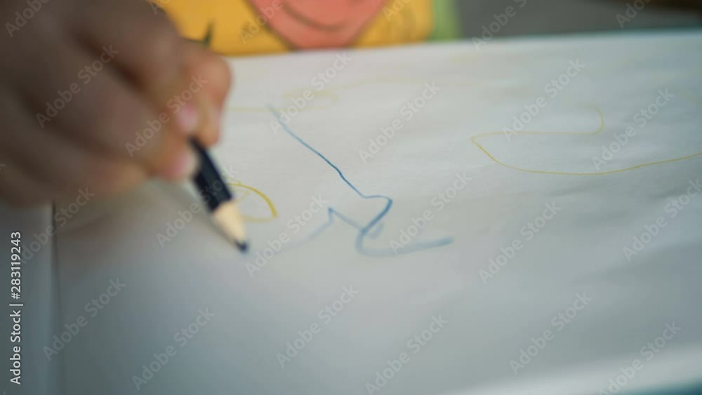 small child hand draws on white paper sheet with pencil small child hand draws on white paper sheet with pencil