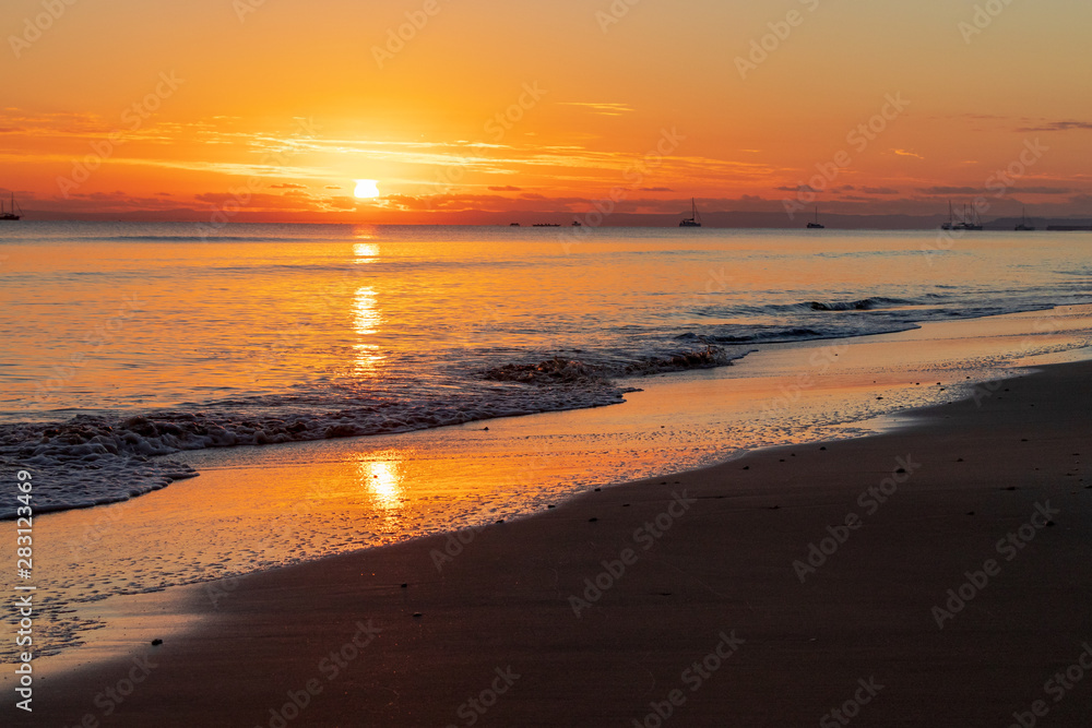 Sun rising over ocean shore