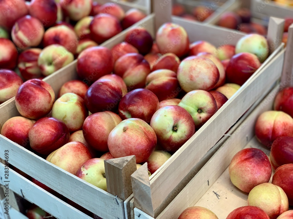 Fresh, ripe nectarines in wooden boxes for sale at a market. Close up. Fruit, summer concept. Fresh, ripe nectarines in wooden boxes for sale at a market. Close up. Fruit, summer concept.