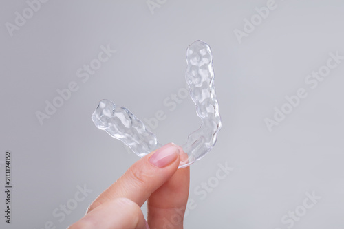 Obraz na plátně Woman's Hand Holding Plastic Braces Over Gray Backdrop