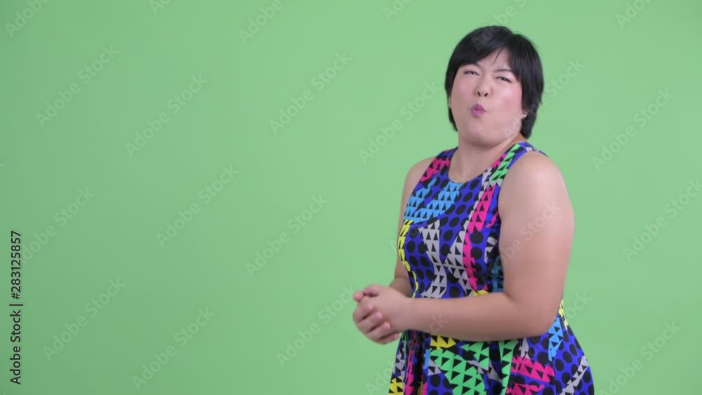 Happy young overweight Asian woman showing to back and looking surprised Happy young overweight Asian woman showing to back and looking surprised