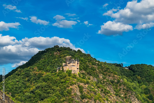 View of hilltop castle on the side of Rhine River at beautiful summer day in Germany. Rhine Valley is UNESCO World Heritage Site.