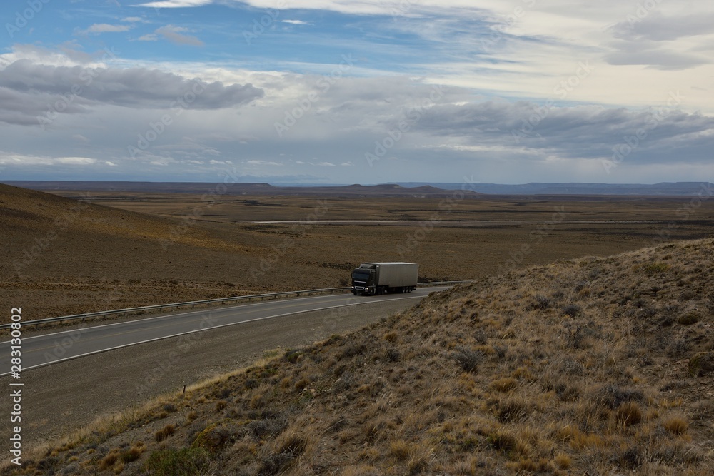 Camion de carga subiendo con paisaje desertico y cielo nublado de fondo