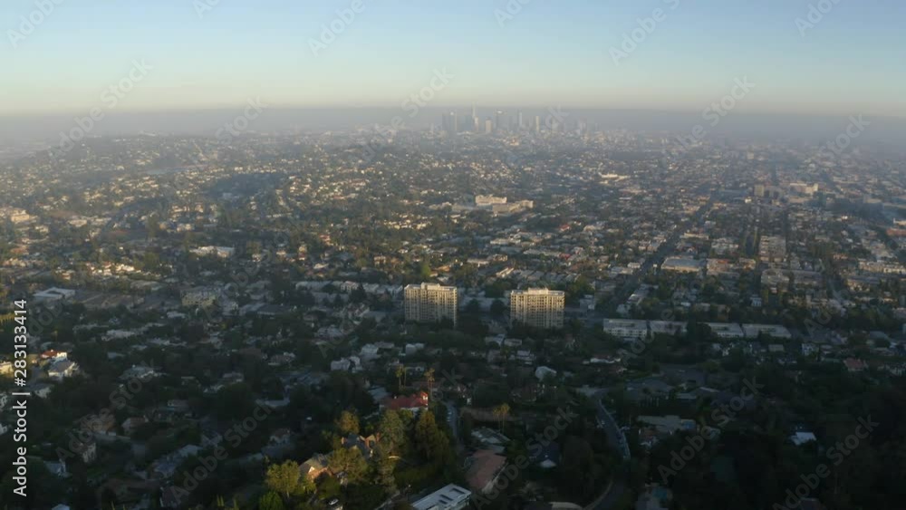 Aerial, tracking, drone shot, panning over the Griffith park, overlooking the cityscape, the downtown Los angeles, in the background, on a sunny, summer day, in Los Feliz, California, USA Aerial, tracking, drone shot, panning over the Griffith park, overlooking the cityscape, the downtown Los angeles, in the background, on a sunny, summer day, in Los Feliz, California, USA