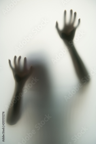 Obraz na płótnie The dark shadow of the hands and body behind the opaque glass makes it look scary in the Halloween concept. w salonie