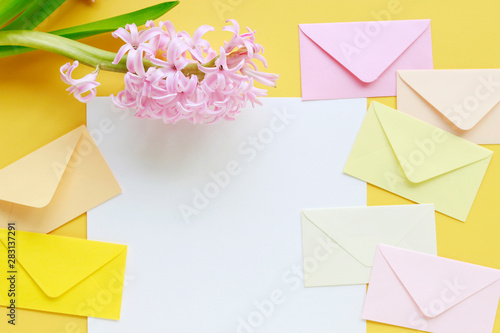 Colorful envelopes and hyacinth flowers on yellow background