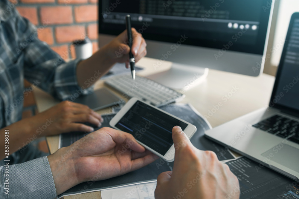 Software developers are using smart phones and analyzing together the code written in the program on the computer. Software developers are using smart phones and analyzing together the code written in the program on the computer.