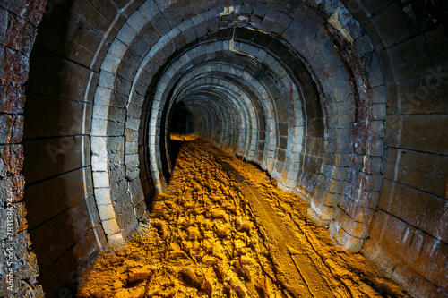 Dark dirty abandoned uranium mine with rusty remnants of railway photo