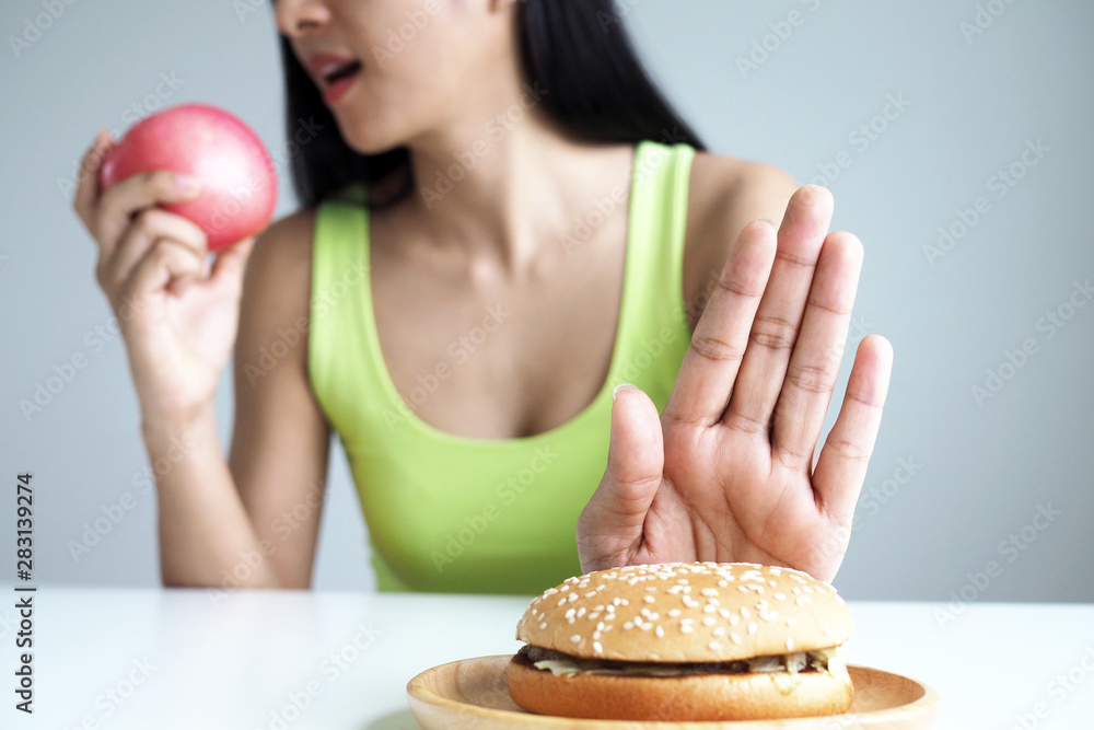 Asian women push the hamburger plate and choose to eat apples for good health. Asian women push the hamburger plate and choose to eat apples for good health.