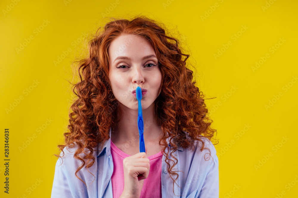 woman redhaired ginger with eco toothbrush and toothpaste on yellow studio background woman redhaired ginger with eco toothbrush and toothpaste on yellow studio background