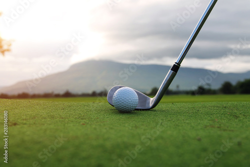 Golf ball and golf club in beautiful golf course at sunset background. Golf ball on green in golf course at Thailand