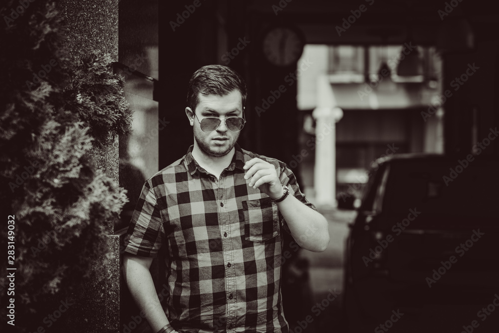Portrait of young modern handsome man in blue plaid shirt and jeans at the city. Citizen lifestyle Portrait of young modern handsome man in blue plaid shirt and jeans at the city. Citizen lifestyle