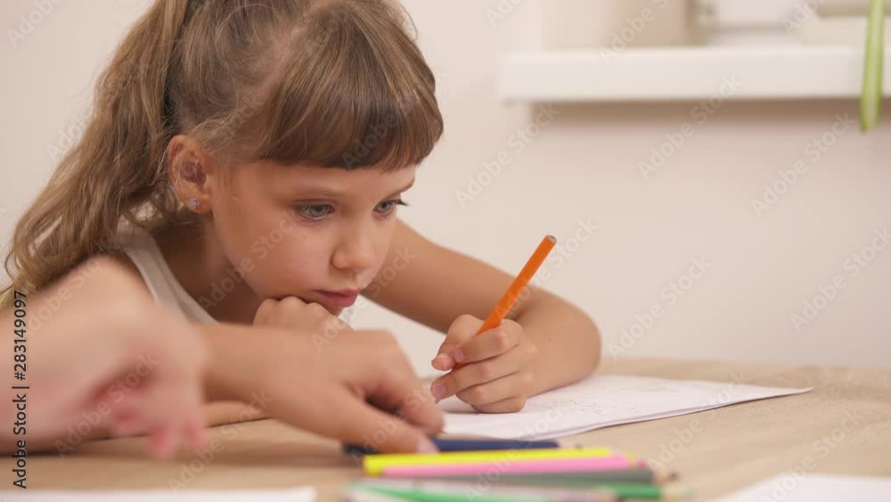 Close-up of cute little girl drawing with colored pencils during psychological session. Professional therapist doing projective psychological test. Close-up of cute little girl drawing with colored pencils during psychological session. Professional therapist doing projective psychological test.