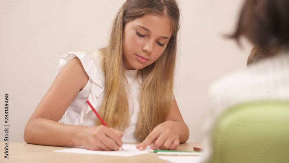 Portrait shot of a beautiful teenage girl drawing with pencils. Clinical psychologist doing psychological test. Portrait shot of a beautiful teenage girl drawing with pencils. Clinical psychologist doing psychological test.