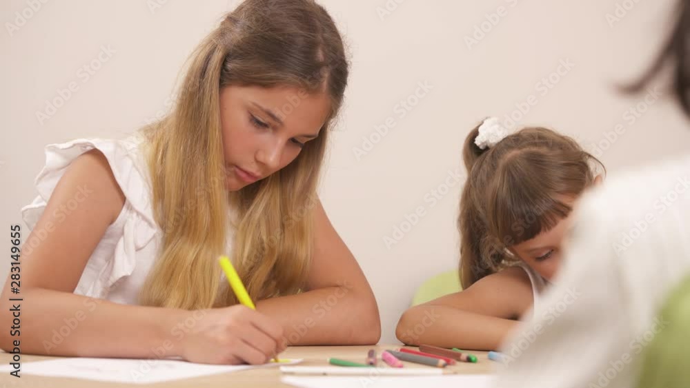 Little sisters in child occupational therapy session drawing with the professional psychologist in a family support center. Little sisters in child occupational therapy session drawing with the professional psychologist in a family support center.