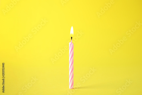 Obraz na plátně Burning pink striped birthday candle on yellow background