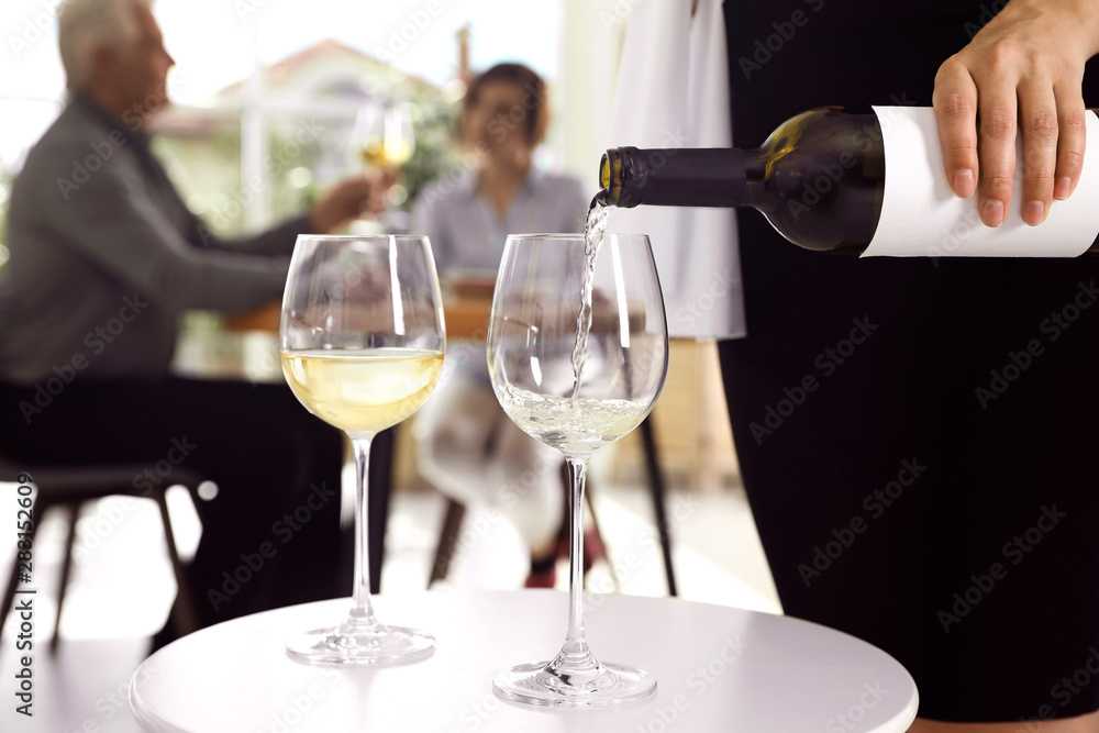 Waitress pouring wine into glass in restaurant, closeup Waitress pouring wine into glass in restaurant, closeup